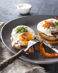 A healthy Breakfast with whole wheat toasts and Poached egg with green salad, bacon and pepper. Rustic style on dark background. Vertical.