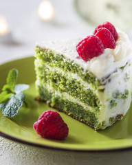 Homemade spinach crepe cake with cheese cream close-up on a plate on a table.