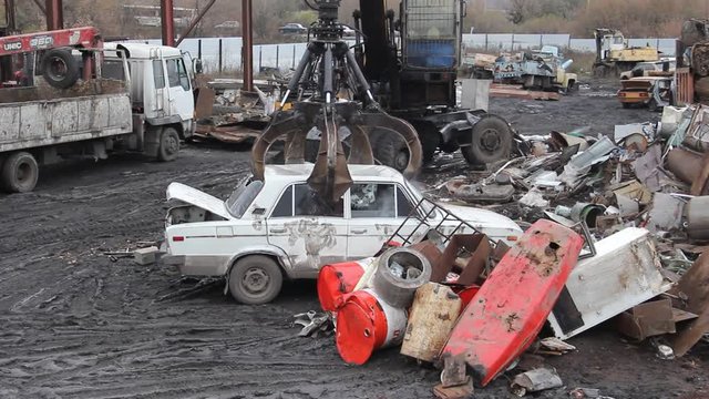 Sorting and loading of scrap metal/Excavator is loading scrap metal junk into a bin at a garbage dump or recycling center.