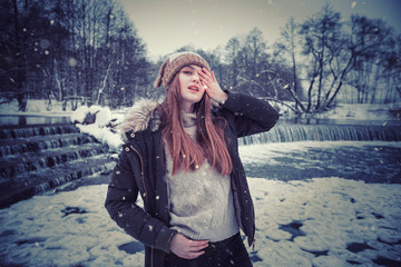Model posing girl posing against a background of winter nature. Dressed for winter beautiful appearance, long hair