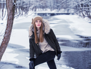 Model posing girl posing against a background of winter nature. Dressed for winter beautiful appearance, long hair