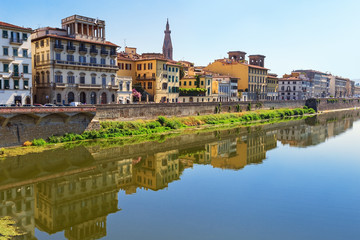 Obraz premium Buildings on the banks of the Arno River in the city of Florence. Italian architecture. Urban landscape in Italy. Reflections on water. June 2017.
