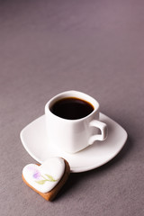 a cup of espresso and a group of cookies with aysing in the shape of a heart on a gray background, conciseness, minimalism