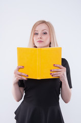 Business woman in black dress holds the yellow book in hands. Isolated on white background. Place for text and logo