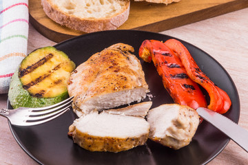 Fried chicken fillet with vegetables on a black plate close-up, macro