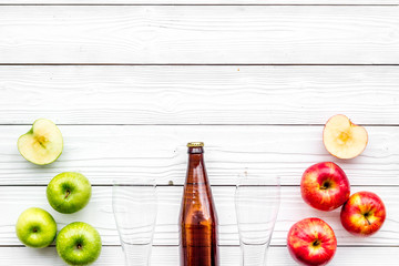 Apple cider. Low-alcoholic beveradge in dark bottle near beer glasses and fresh apples on white wooden background top view copy space