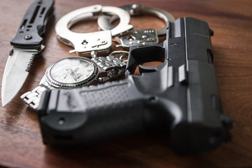 Tactical gear set of Pistol gun knift handcuff and clock on wooden background. Police or military equipment concept.