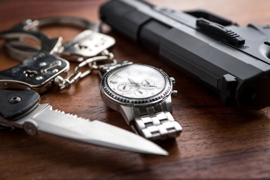 Tactical gear set of Pistol gun knift handcuff and clock on wooden background. Police or military equipment concept.