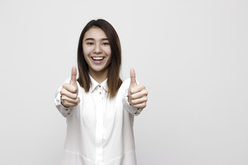 Enthusiastic motivated attractive young woman giving a two thumbs up gesture of approval and success with a beaming smile. Selective focus and shallow DOF