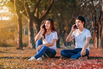 young couple talking on mobile phone in park