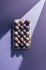Easter purple eggs in big tray on purple background with sunbeam