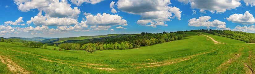 Blue cloudy sky over green hills and country road