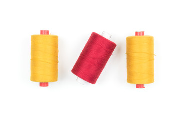 Yellow and red thread coils on white background, sewing and tailoring supplies