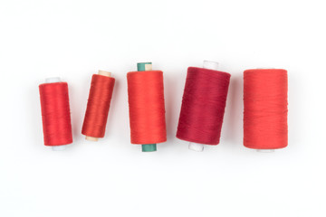 Row of five red colour thread coils on a white background, sewing and tailoring supplies