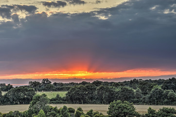The sun sets of a gently sloping landscape with scattered trees in central France