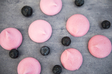 Pink meringues with blueberries on a grey background