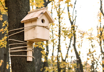 Red birdhouse or nesting box hanging on a tree.