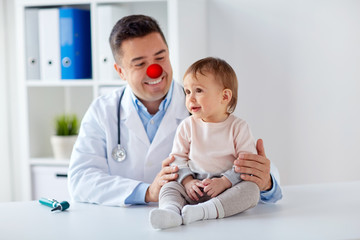 Fototapeta premium happy baby girl at doctor on red nose day