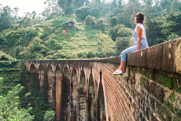 Woman sits on the Demodara nine arches bridge the most visited sight of Ella town in Sri Lanka