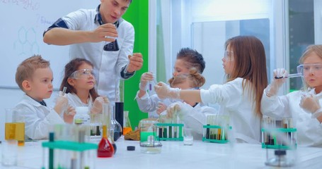 Teacher explaining an experiment to a high school chemistry class together. Teacher and children in chemistry class - Powered by Adobe
