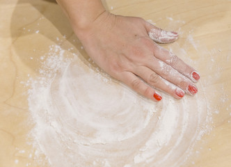 Fototapeta premium Female hand rubbing flour on the dough.With the blur effect