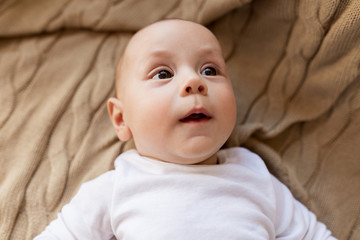 sweet little baby boy lying on knitted blanket