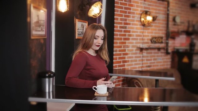 The girl in the cafe waiting for her boyfriend and use a smartphone