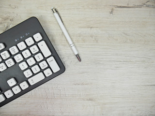 Keyboard and pen on a light wooden background - obrazy, fototapety, plakaty