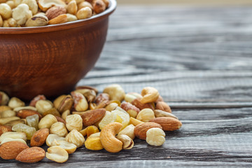 Mix nuts in earthenware on a wooden background.