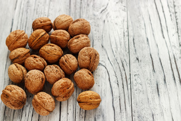 Whole walnuts on a white wooden background.