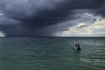 sea with anchoring boat and dark storm clouds on the horizon