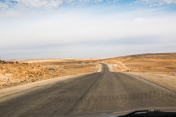 Desert highway and mountains through car window not far from Dead sea