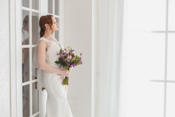 Gentle bride waiting for the groom standing near the door.