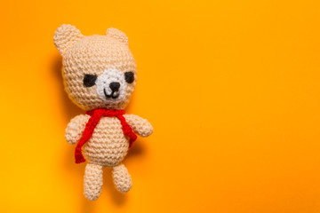 Hand made knitted wool bear on yellow background