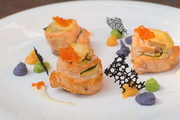 Seafood - salmon with cucumber, decorated with red caviar, sauce on white plate. Selective focus 