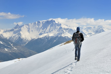 Naklejka na ściany i meble hiker walking on the snow in a beautiful alpine mountain 