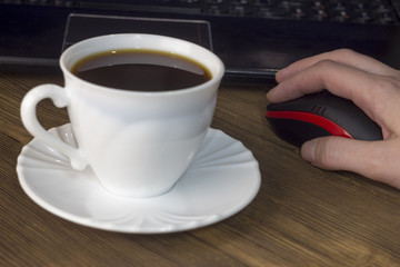 A cup of coffee computer, mouse, hand, wooden background
