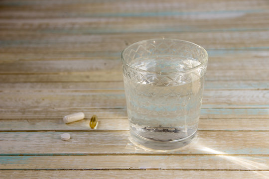 Glass with water and medicine pills near it