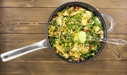 Stewed vegetables in a frying pan on a wooden background