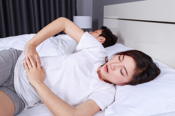 Obraz na płótnie Canvas woman stomach pain on bed with her hunsband