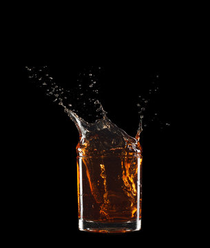 Glass of whiskey with splash isolated on black background