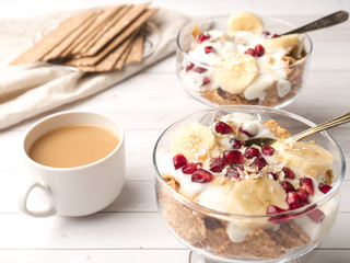 Glass bowl with muesli and yogurt with banana, pomegranate seeds