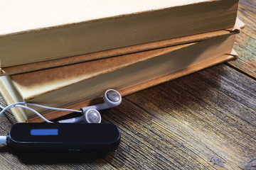mp3 player and headphones. books. on a wooden table.  Audiobook concept. - obrazy, fototapety, plakaty