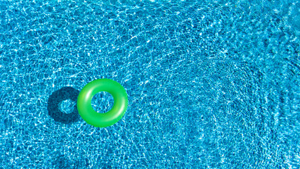 Fototapeta na wymiar Aerial view of colorful inflatable ring donut toy in swimming pool water from above, family vacation holiday resort background 