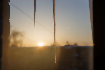 icicles hang from the roof at sunset