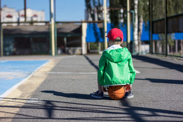 Alone boy sitting back on basketball
