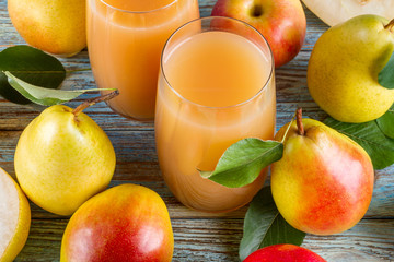 Fresh organic farm pear juice in glass with raw whole and sliced pears on woody background