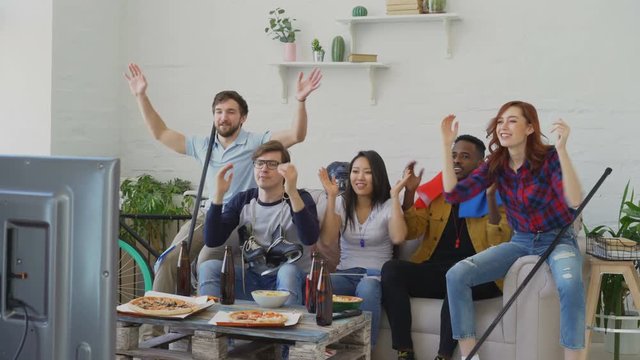 Diverse group of friends sports fans with French national flags watching TV