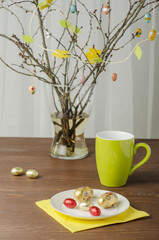 Easter tree and flowers with chocolate eggs on a wooden table