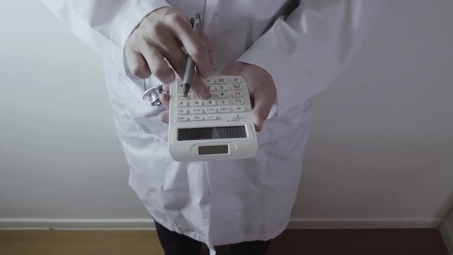 Healthcare costs and fees concept.Hand of smart doctor used a calculator for medical costs in modern hospital